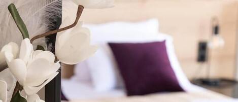 A bedroom with a bed, a bedside table, a vase with flowers, and a decorative gold figure.