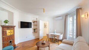 Un salon moderne comprenant un téléviseur à écran plat, une table à manger avec des chaises, un canapé et un meuble décoratif.