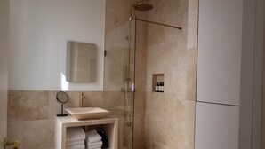 A modern bathroom with a glass-enclosed shower, a vanity with a sink, and a mirror.