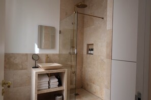 A modern bathroom with a glass-enclosed shower, a vanity with a sink, and a mirror.