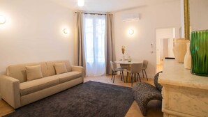 Un salon comprenant un canapé, une table à manger avec des chaises, un petit tapis et un vase décoratif.