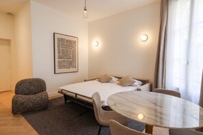 A modern bedroom with a bed, a chair, a round table, and a wall-mounted light fixture. - Madeleine Opéra - Excellent One Bedroom in Paris (Paris)