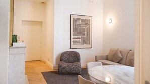 A modern living room with a sofa, a small armchair, a marble coffee table, and a framed abstract artwork on the wall.