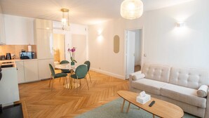 Een moderne woonkamer met een bank, een houten salontafel en een eetgedeelte met stoelen en een tafel.