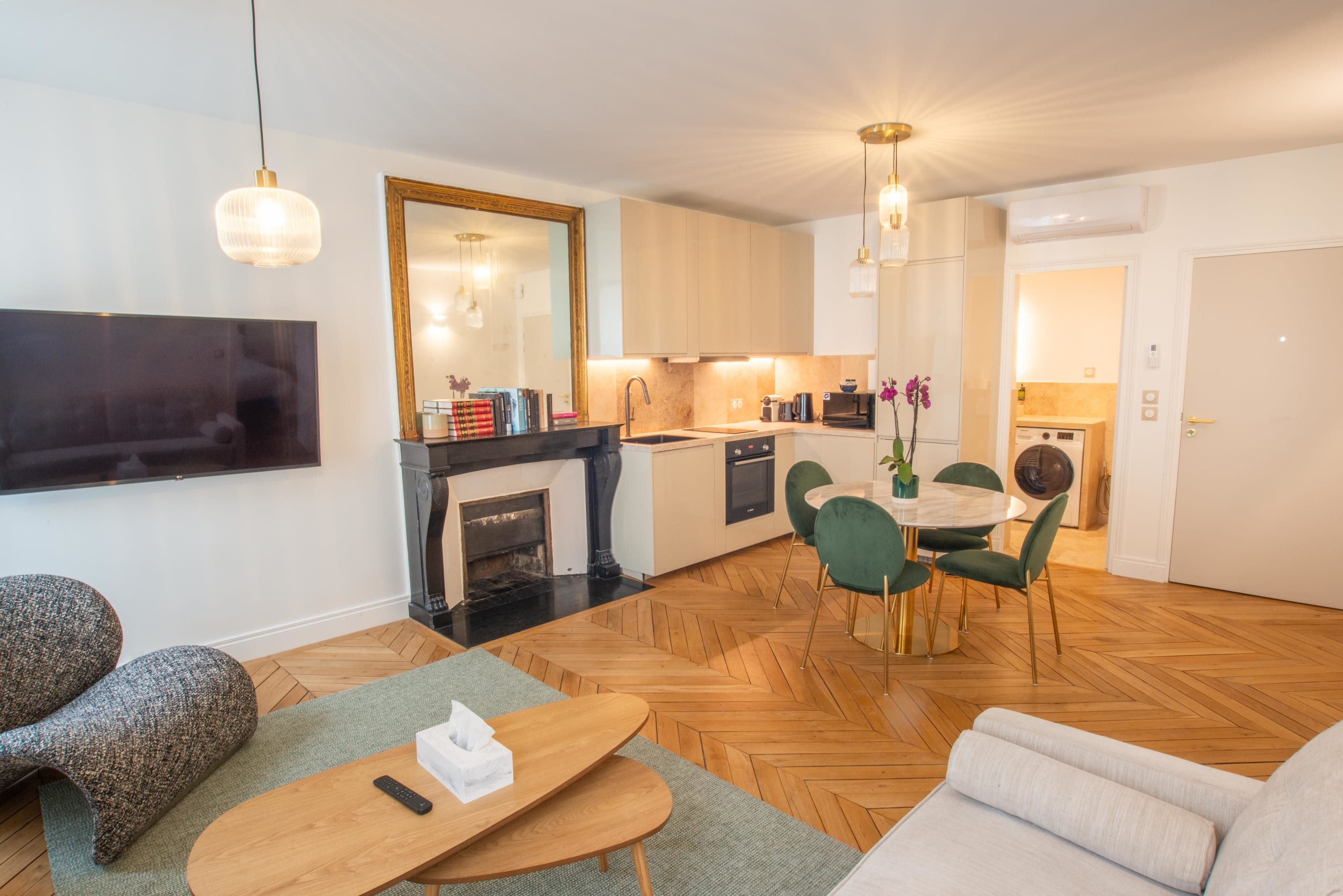 Uma sala de estar moderna com lareira, área de jantar com cadeiras verdes e cozinha com armários de madeira.