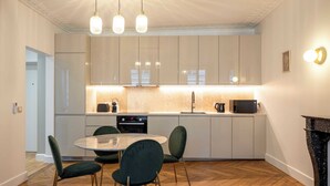 Een moderne keuken met witte kasten, een ronde eettafel en groene stoelen.