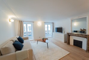 A modern living room with a sofa, a coffee table, a fireplace, and a TV. - Madeleine Opéra - One Bedroom Deluxe in Paris (Paris)