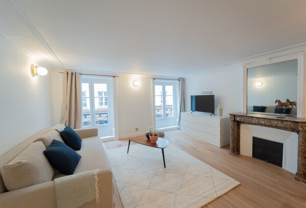 A modern living room with a sofa, a coffee table, a fireplace, and a TV.