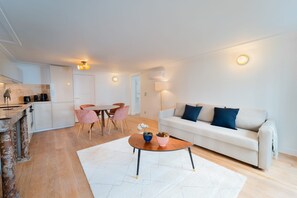 A modern living room with a sofa, coffee table, and dining area. - Madeleine Opéra - One Bedroom Deluxe in Paris (Paris)