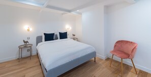 A bedroom with a bed, two bedside tables, a nightstand, a chair, and a skylight. - Madeleine Opéra - One Bedroom Deluxe in Paris (Paris)