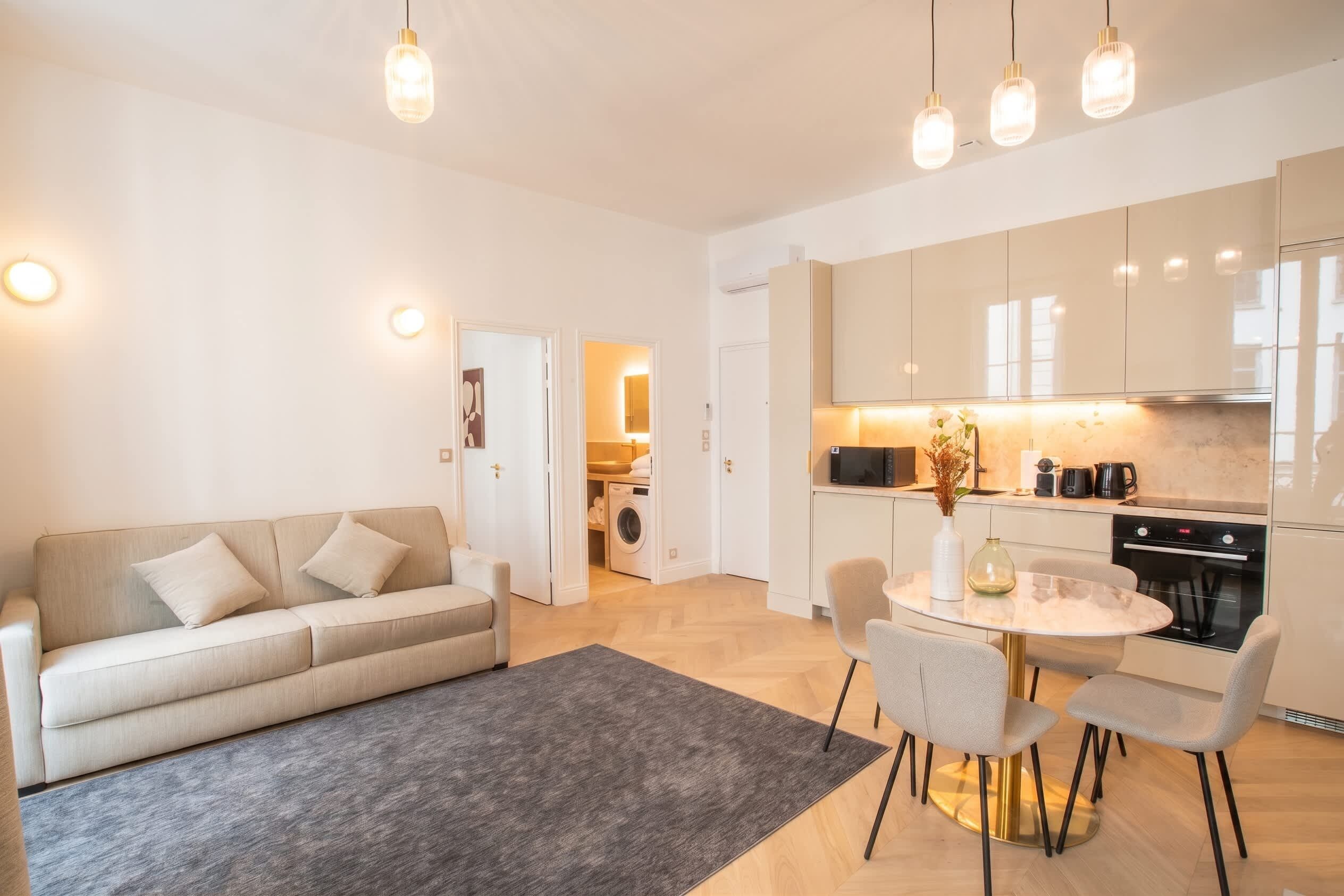 A modern apartment with a living area, kitchenette, and a dining space.