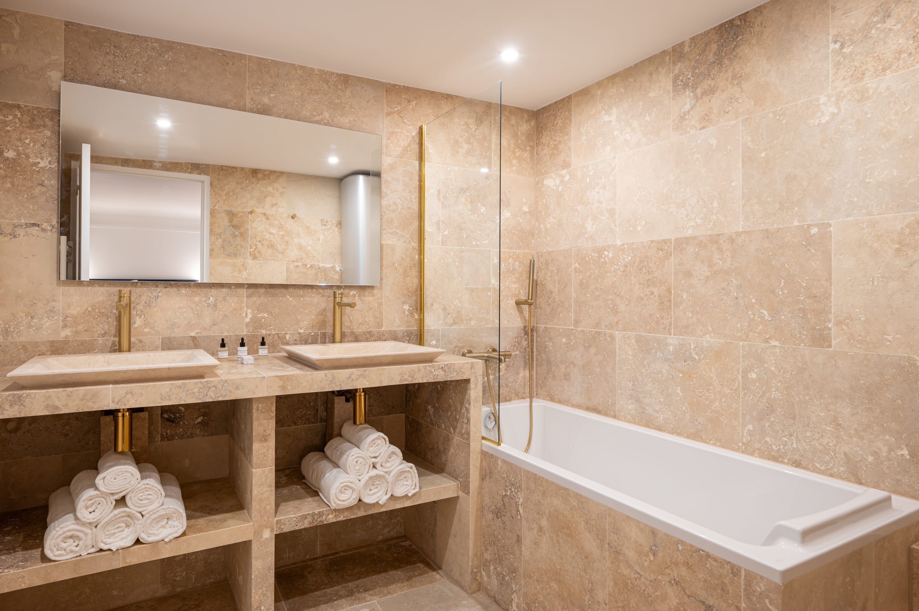 Une salle de bain moderne avec deux lavabos, un grand miroir, une douche à parois de verre et une baignoire blanche.