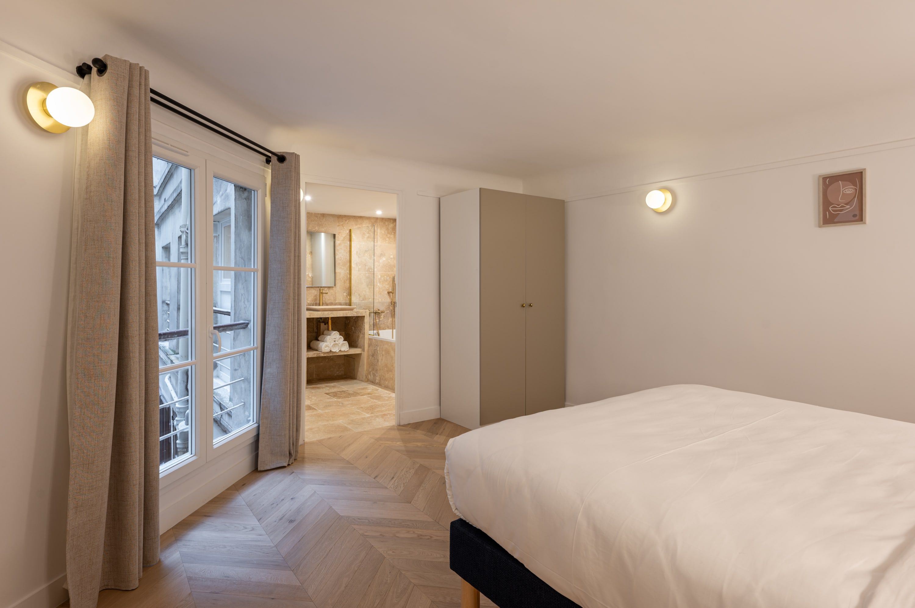 A bedroom with a bed, a wardrobe, and a bathroom visible through an open door.