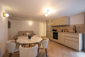 A modern kitchen with a round dining table, light-colored cabinets, and a built-in oven.