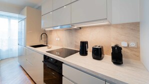 A modern kitchen with a large island, built-in appliances, and a window providing natural light.