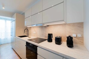 A modern kitchen with a large island, built-in appliances, and a window providing natural light.