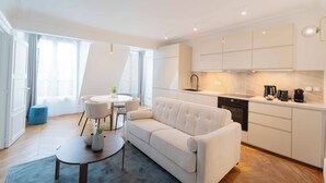 A modern living room with a sofa, a coffee table, and a dining area with chairs.