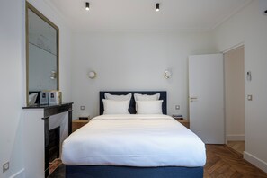Un dormitorio moderno con una cama grande, una chimenea y un espejo en la pared.