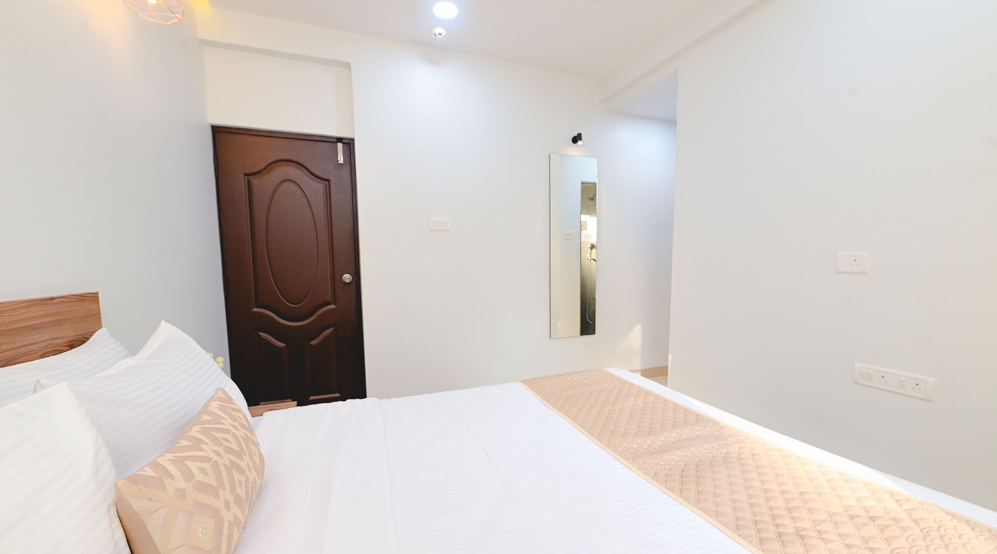 Una camera da letto con un letto, una porta in legno, uno specchio e un lampadario.