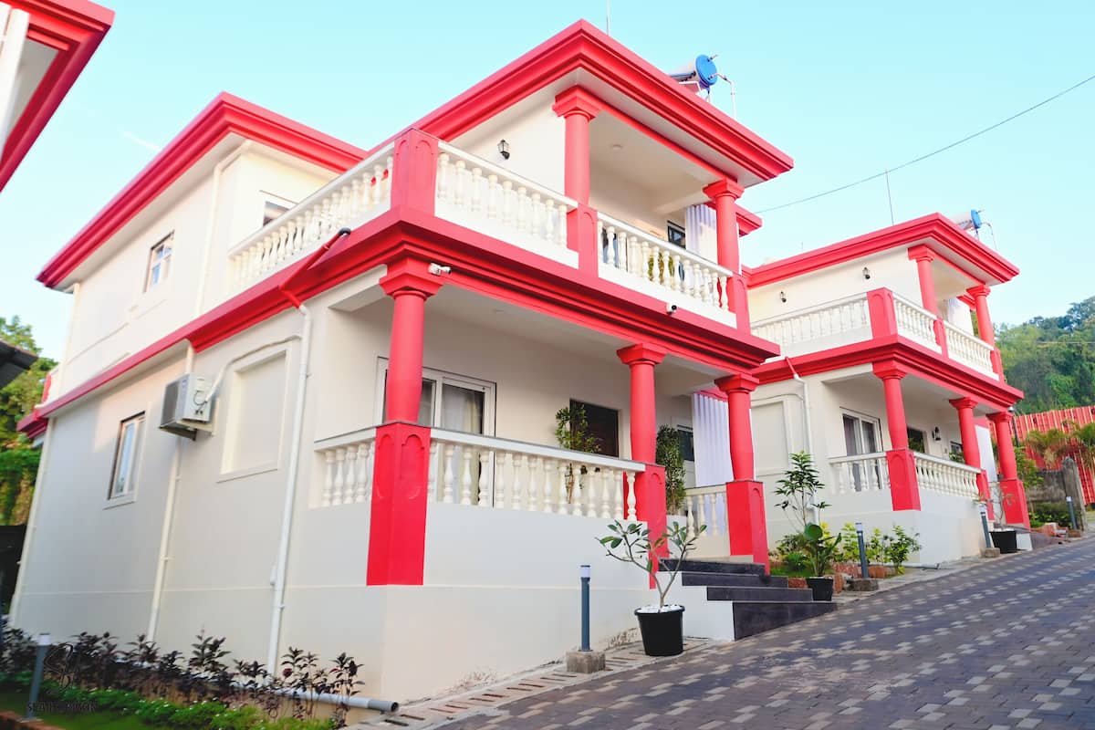 A two-story house with a red and white exterior, balconies, and potted plants.
