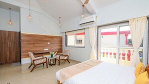 A hotel room with a bed, a desk, two chairs, and a window with a view.