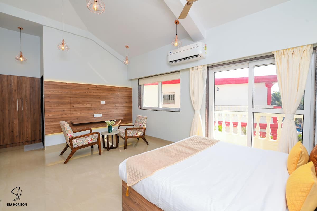 A hotel room with a bed, a desk, two chairs, and a window with a view.