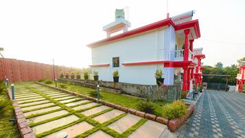 Ein Gebäude mit roter und weißer Fassade, ein gepflasterter Garten mit trittfesten Steinen und ein kleines Fenster.