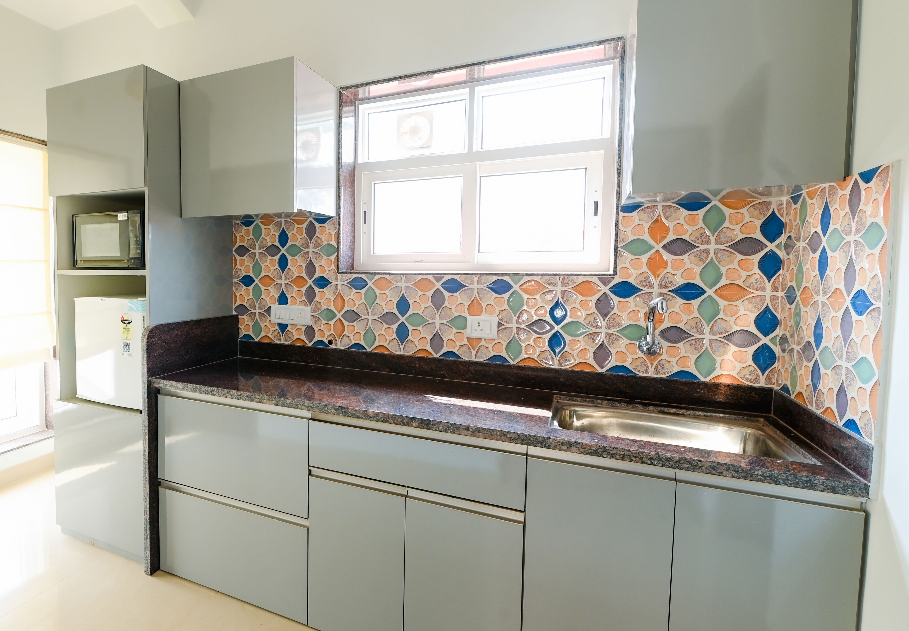 Una cocina con salpicadero de azulejos, una ventana y armarios empotrados.