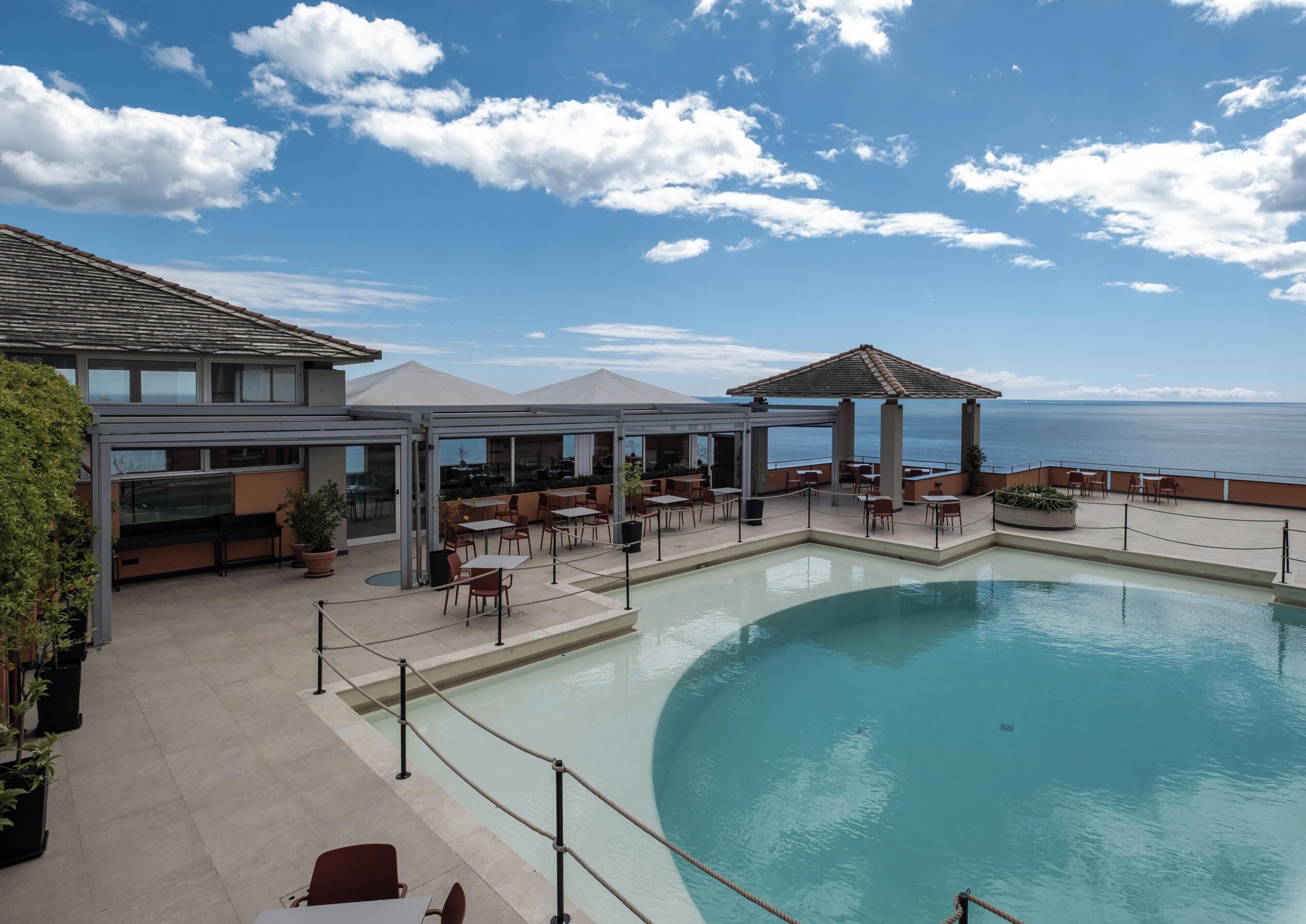 A poolside area with outdoor seating and a view of the sea.