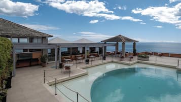 A poolside area with outdoor seating and a view of the sea.