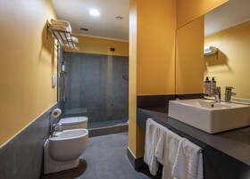 Een moderne badkamer met toilet, bidet en een ruime wastafel met spiegel.