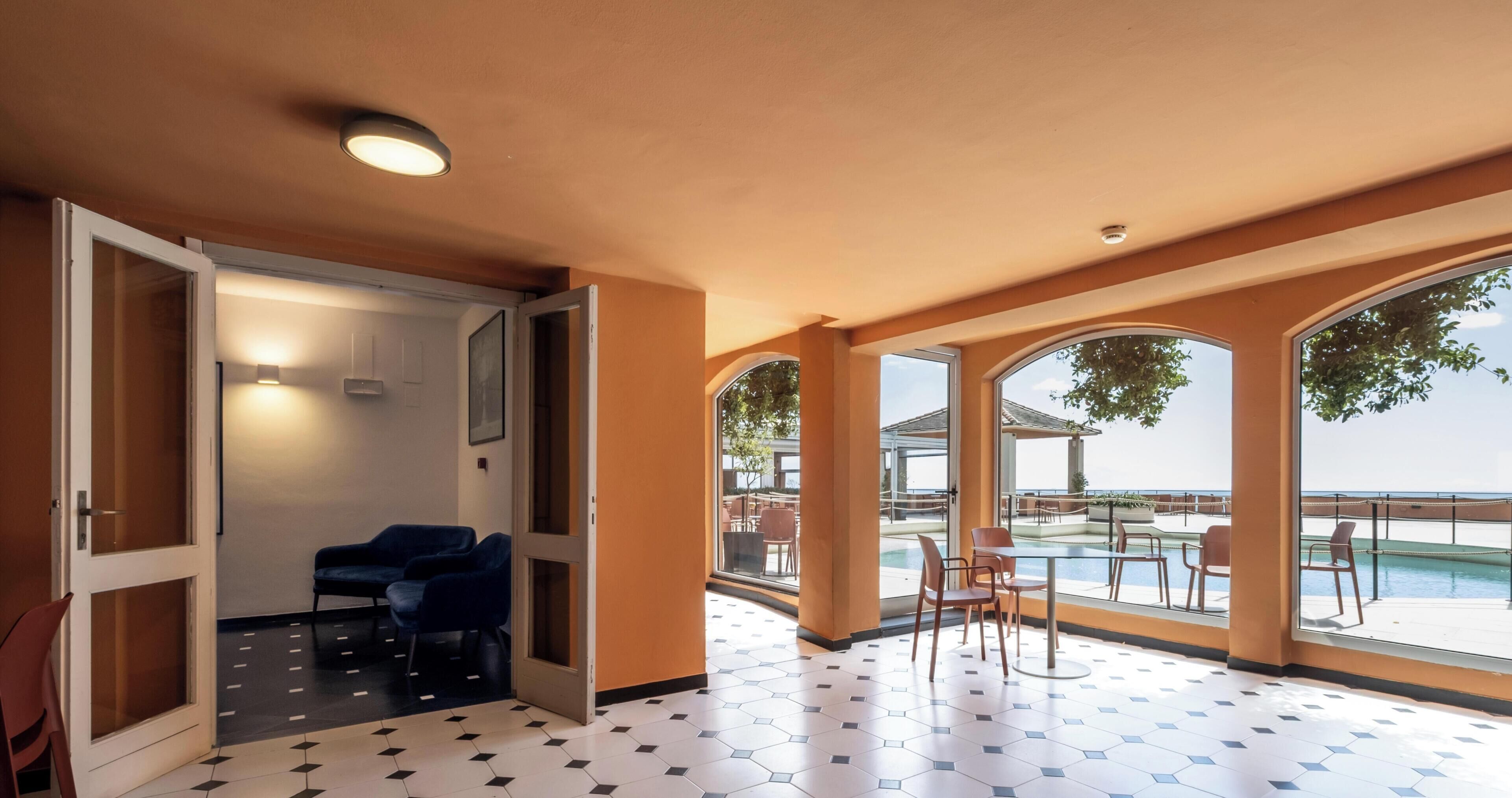 A hotel room with a view of the pool and outdoor seating.