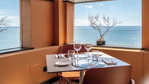 A dining table with a clear view of the sea through large windows. - Hotiday Arenzano Pineta (Arenzano)