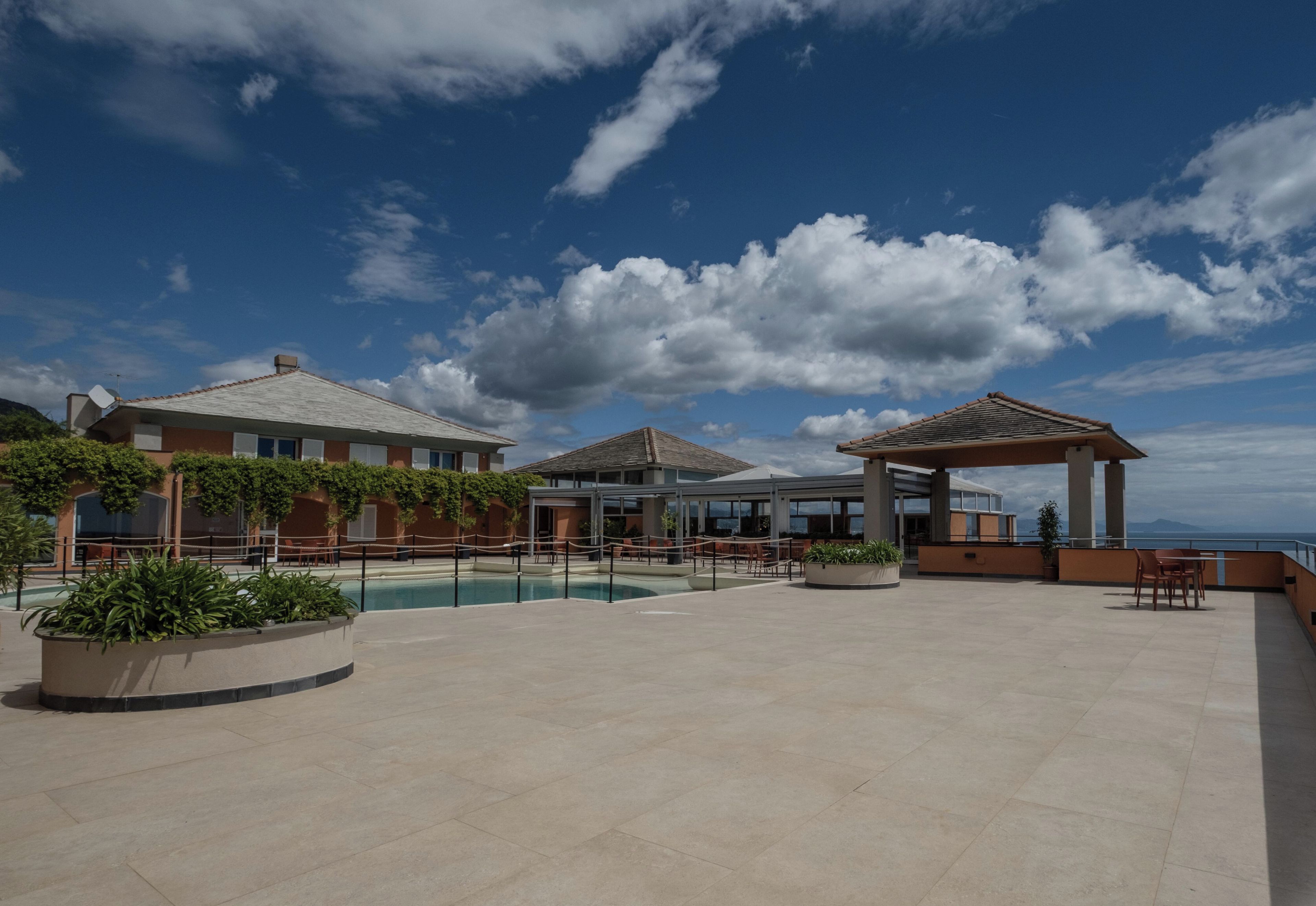 A rooftop pool area with a pergola, seating, and a view of the ocean.