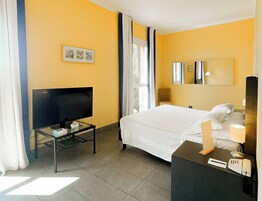A hotel room with a bed, a TV, a desk with a phone, and a mirror.
