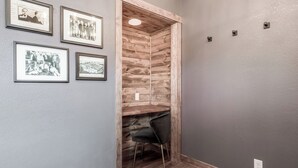 Ein Flur mit gerahmten Fotografien an der Wand, einer Holzwand als Blickfang und einem schwarzen Sessel in der Ecke.