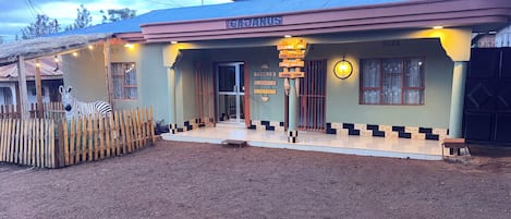 A building with a sign indicating it is a CAJANGAS, featuring amenities like a dining and top bar, free Wi-Fi, and a Karibu Sana.