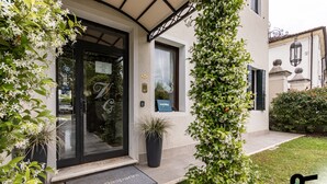 A hotel entrance with a glass door, a doormat, and a sign indicating 'holiday villa'. - Hotiday Room Collection - Dolo (Dolo)