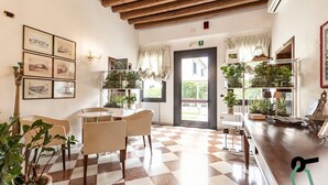 A dining area with a checkered floor, wooden ceiling, and a view of the outside through a door. - Hotiday Room Collection - Dolo (Dolo)