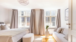 A modern bedroom with a bed, a sofa, a small table, and a potted plant. - Regent 15 - Bright 1 Bdr Apt Right in the Centre of Copenhagen (Copenhagen)