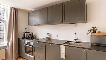 A modern kitchen with grey cabinets, a built-in oven, and a stainless steel sink.