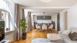 A modern living room with a sofa, a marble coffee table, and a dining area with chairs. - Regent 15 - Bright 1 Bdr Apt Right in the Centre of Copenhagen (Copenhagen)