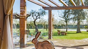 A wooden rabbit sculpture on a vintage suitcase in a covered outdoor area with a view of a garden and trees. - Podere La Troscia is an enchanting Rustic Villa in the Versilia countryside on the Tuscan coast with Garden and Private Pool; the owners love to share this wonderful place with guests from all over the world who intend to visit the North of Tuscany, the  (Piano di Mommio)