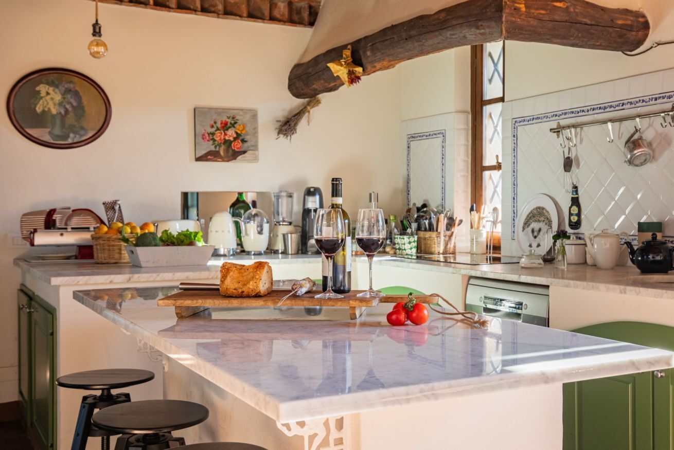A kitchen with a marble island, green cabinets, and various kitchen items.