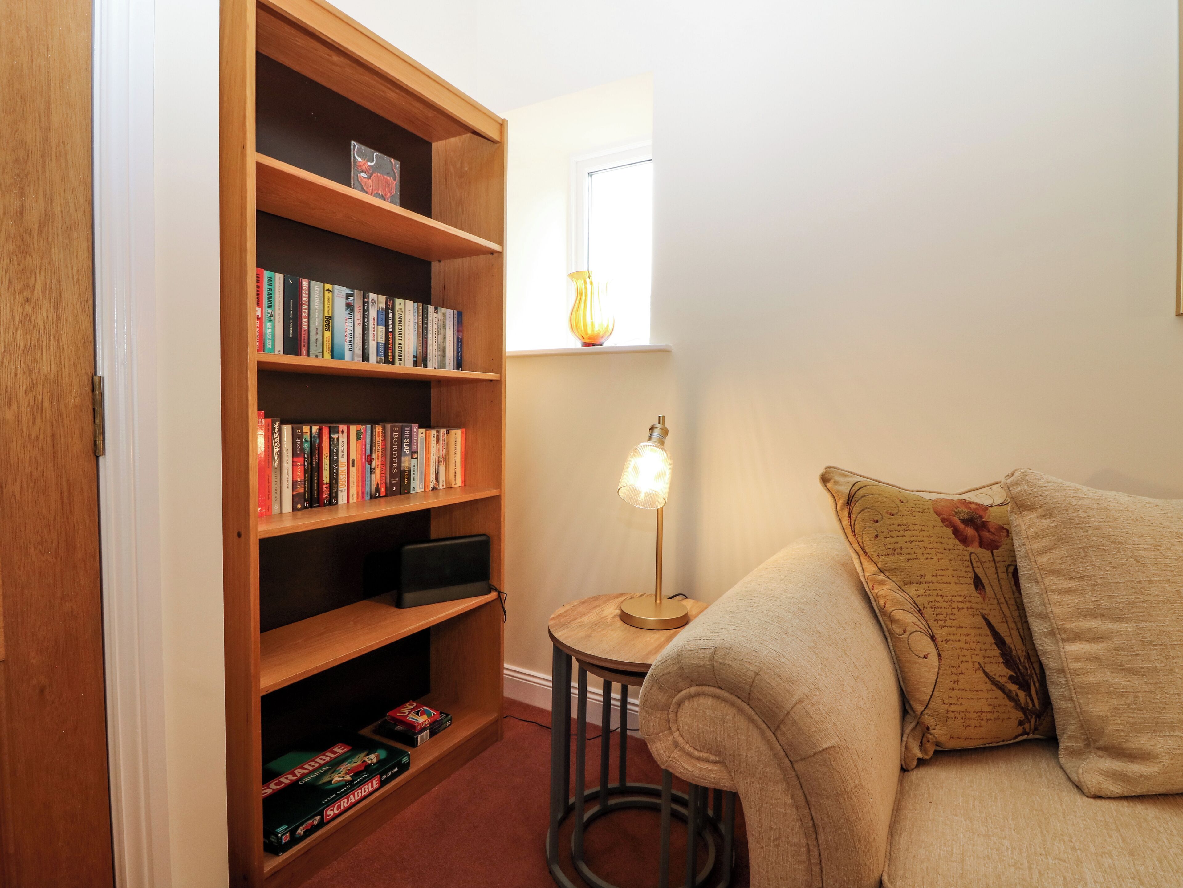 A cozy reading nook with a bookshelf, a small table with a lamp, and a comfortable sofa.