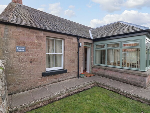A cottage with a stone facade, a small front garden, and a sign reading "Dromore Cottage". - Dromore Cottage (Berwick-upon-Tweed)
