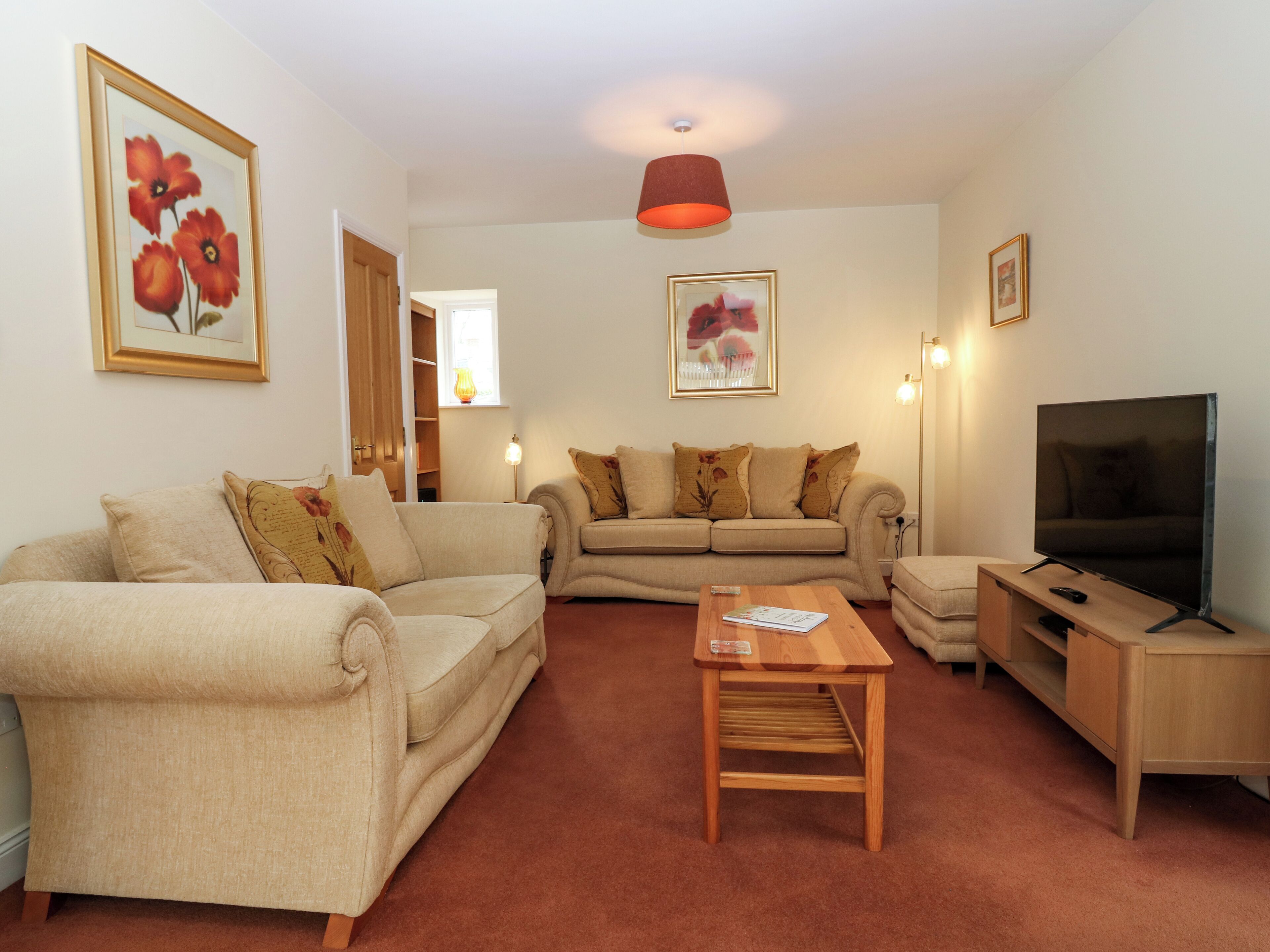 A living room with two sofas, a coffee table, a TV, and framed artwork on the walls.
