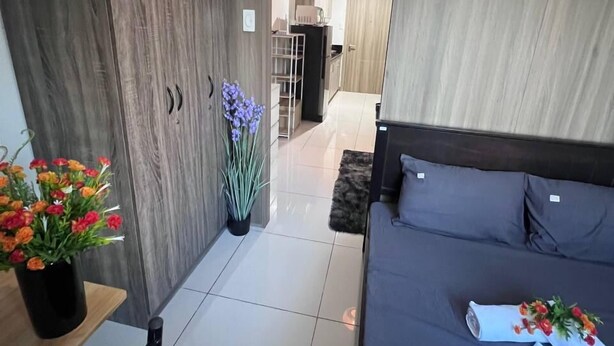 Un dormitorio moderno con cama, escritorio y armario. Hay un pasillo que conduce a una zona de cocina.