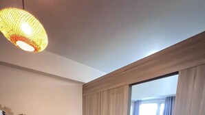 Una sala de estar moderna con un sofá negro, una alfombra mullida y un ventanal con cortinas.
