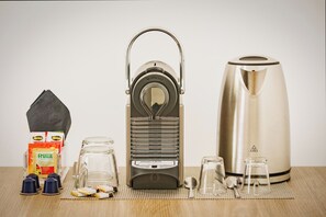 A Nespresso coffee machine, a kettle, a box of coffee pods, a glass jar, and a spoon on a wooden table. - Hotiday Lecce Gianmarti Suite (Lecce)